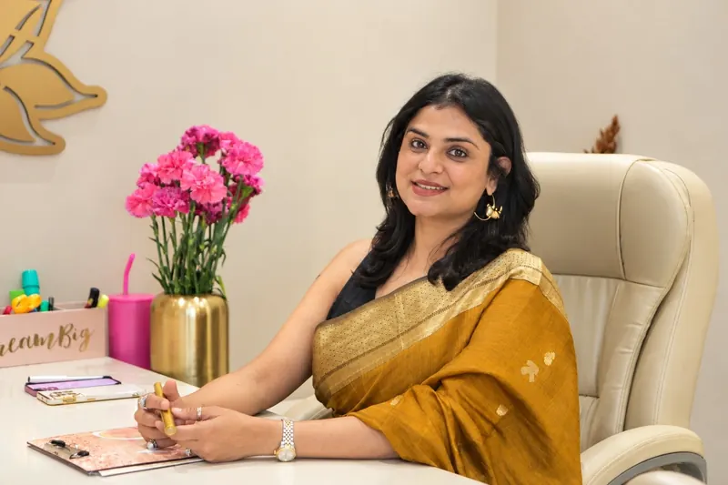 Dr. Anchal Gupta at her desk, in a gold saree with pink carnations