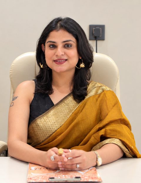 Dr. Anchal Gupta at her desk in a gold silk saree, smiling
