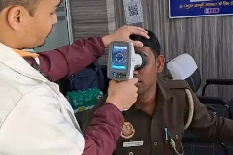 A Delhi Police constable having his sight screened with a handheld autorefractor