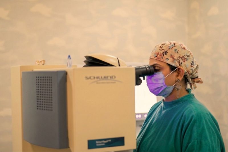 A Netram surgeon in a purple cap at the refractive laser microscope