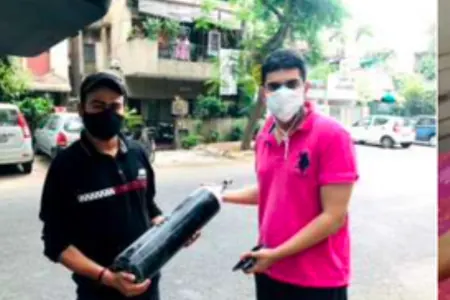 Two volunteers carrying an oxygen cylinder on a Delhi street