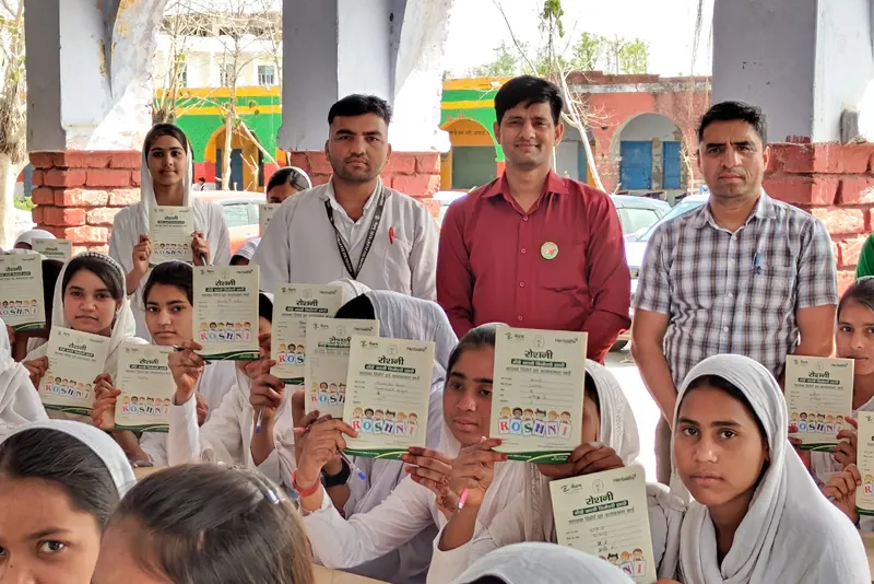 Schoolgirls holding their Roshni cards, with Netram staff behind them